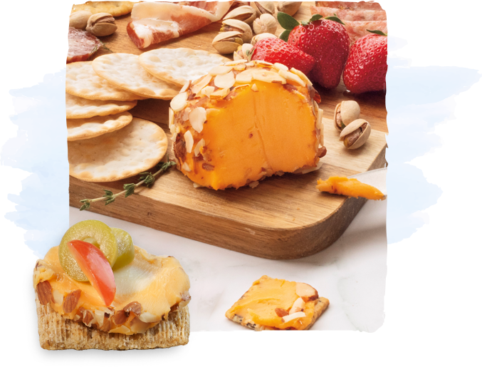 Almond-crusted cheese ball on a wooden board with crackers, pistachios, and strawberries surrounding it